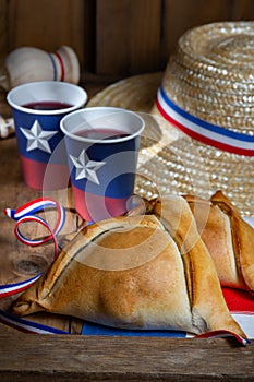 Chilean independence day concept. fiestas patrias. Tipical baked empanadas, wine or chicha, fat and play emboque dish and drink on photo