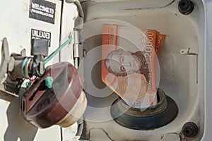 Chilean pesos fitted into a fuel filler or gas hole of a car\'s fuel tank.