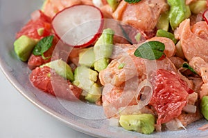 Chilean salmon seviche with grapefruit, avocado, radish, onion and mint in a plate. Healthy diet food photo