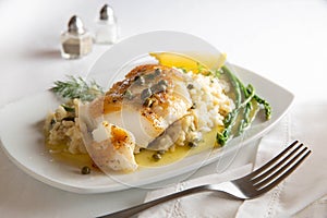 Chilean sea bass with risotto on a white plate