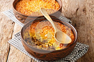 Chilean shepherd`s pie, pastel de choclo tops spiced ground beef with a purÃÂ©ed corn crust closeup in the pots. Horizontal photo