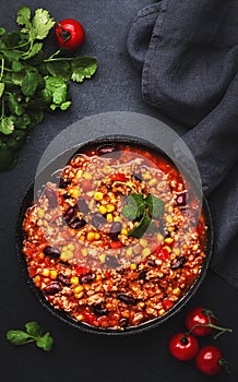 Chili con carne with beef, red beans, paprika, corn and hot peppers in tomato sauce, spicy tex-mex dish in a cooking pot, black