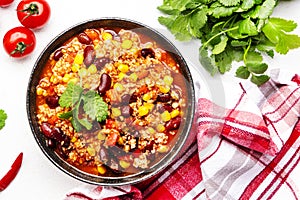 Chili con carne with beef, red beans, paprika, corn and hot peppers in tomato sauce, spicy tex-mex dish, white table background,