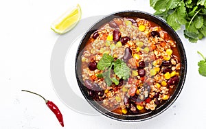 Chili con carne with beef, red beans, paprika, corn and hot peppers in tomato sauce, spicy tex-mex dish, white table background,