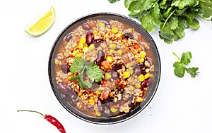 Chili con carne with beef, red beans, paprika, corn and hot peppers in tomato sauce, spicy tex-mex dish, white table background,