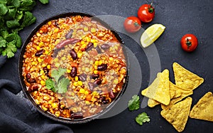 Chili con carne with beef, red beans, paprika, sweet corn and hot peppers in tomato sauce, spicy tex-mex dish in frying pan, black