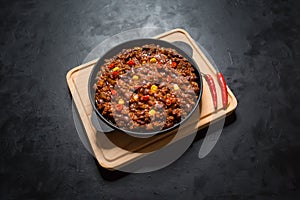 Chili con carne in frying pan on dark background. Texas chili.