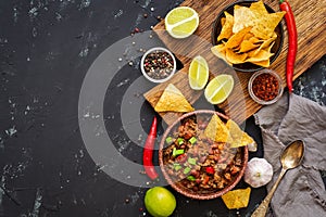 Chili con carne with nachos chips on rustic background.Mexican food. Place for text, top view.