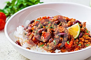 Chili con carne with rice in white bowl. Beef stew with beans in tomato sauce and rice. Traditional Mexican food concept