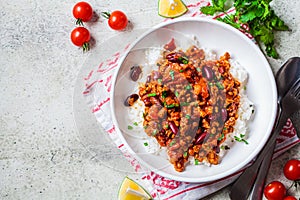 Chili con carne with rice in white bowl, top view. Beef stew with beans in tomato sauce and rice. Traditional Mexican food concept