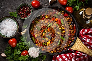 Chili con carne in skillet on dark stone table.