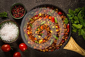 Chili con carne in skillet on dark stone table.