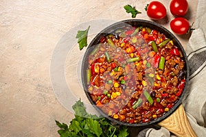 Chili con carne in skillet on dark stone table.