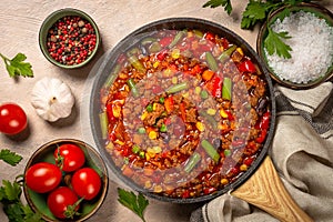 Chili con carne in skillet on dark stone table.