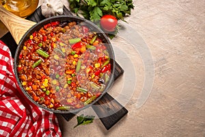 Chili con carne in skillet on dark stone table.