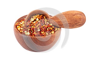 Chili and paprika in wooden bowl and spoon, isolated on white background. Mix of hot and sweet red pepper with grains