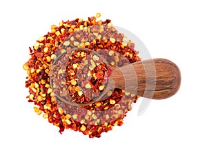 Chili and paprika in wooden spoon, isolated on white background. Mix of hot and sweet red pepper with grains. Close-up