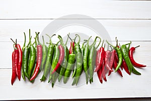 Chili peppers in a row on a white wooden background