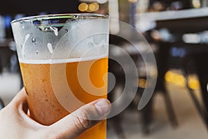 Chill beer holding by hand on dark background