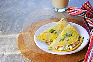 Chilla, tortillas or pancakes made from chickpea flour stuffed with cheese panir and tomato on a white plate