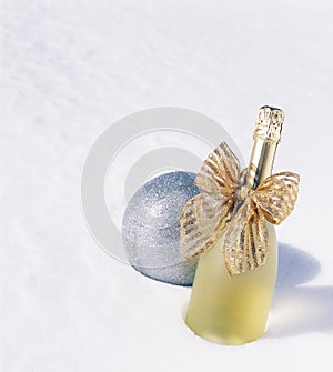 Chilled cold bottle of Champagne sparkling wine and glitter ornament in snow