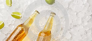 Chilled drink for summer heat. Glass bottles with light beer without labels in ice with pieces of lime