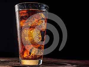 Chilled glass of cola drink with ice cubes isolated on dark background