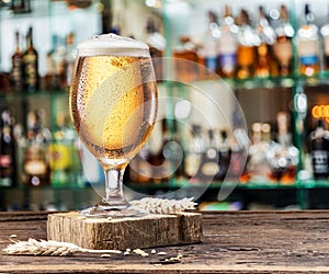 Chilled glass of light beer on the bar counter. Blurred bar background