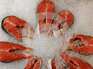 Chilled salmon steaks lie in ice on a store counter. Red fish meat in a seafood supermarket.