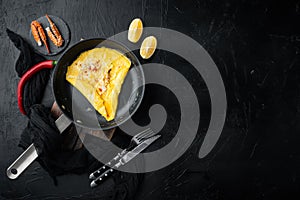 Chilli crab silky omlette , on frying iron pan, on black background, top view flat lay  , with copyspace  and space for text