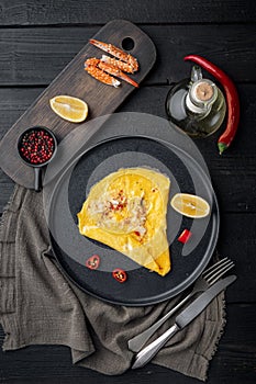 Chilli crab silky omlette , on plate, on black wooden table background, top view flat lay