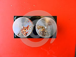 Chilli flakes and oregano spices stored in small cans