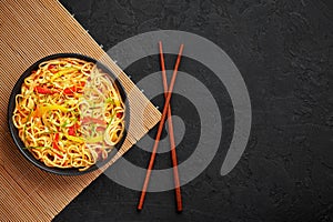 Chilli Garlic Hakka Noodles in black bowl on dark slate table top. Indo-Chinese vegetarian cuisine dish