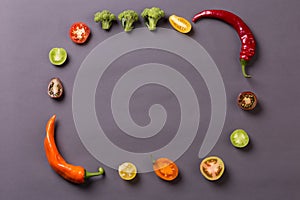Chilli peppers with tomatoes and broccoli on grey background compose frame