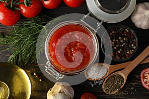 Chilli sauce, garlic, tomatoes, olive oil, spices on wooden background, close up. Top view