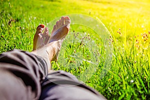 Chilling in the green grass: Legs of a young man, relaxing, summertime