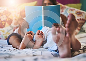 Chilling with a relaxing read. Closeup shot of a mother and her little daughters bare feet at home.