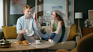 Chilling spouses drinking tea at sofa interior. Couple enjoying coffee talking