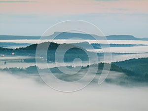 Chilly fall atmosphere in countryside. Cold and damp autumn morning, the fog is moving in valley between dark forest hills.