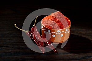 Chilly powder in clay pot with red chilly, dried chillies on wooden background