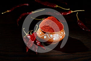 Chilly powder in clay pot with red chilly, dried chillies on wooden background