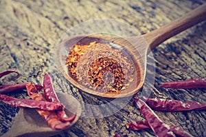 Chilly powder with red dried chilies in wooden spoon on old wooden
