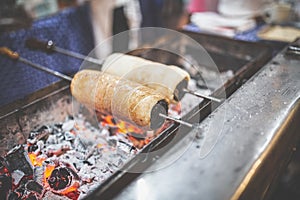 Chimney cake rolls spinning over hot coals at market stand