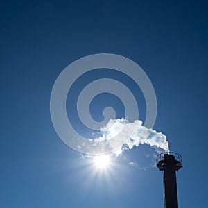 Chimney exhausting steam in blue sky photo