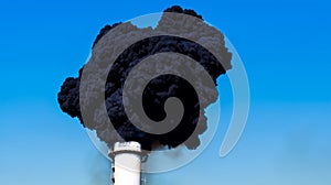 Chimney of the industrial plant emitting dense black smoke polluting and carcinogenic photo