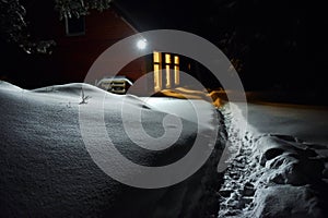 Chimney light of a cottage illuminate the snow outside at winter