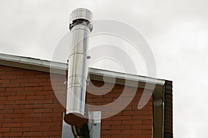 Chimney made of steel installed on the top floor with a brick wall background