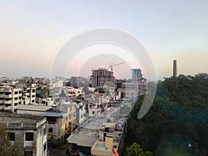 Chimney of an old mill and a high rise under construction building with a big crane in an Indian tier 2 city