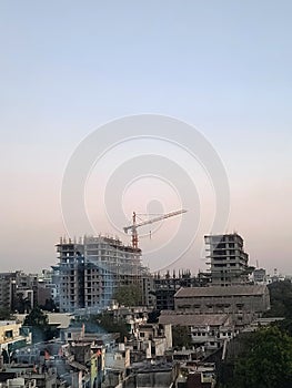 Chimney of an old mill and a high rise under construction building with a big crane in an Indian tier 2 city