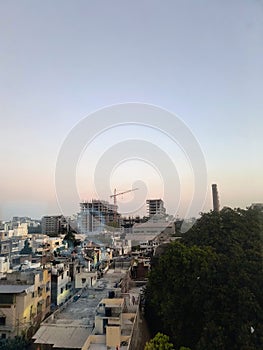 Chimney of an old mill and a high rise under construction building with a big crane in an Indian tier 2 city
